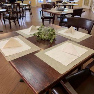 A neatly arranged table in a restaurant dining area with place settings and decorative centerpiece.