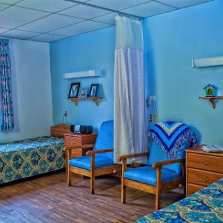 A serene hospital room featuring two beds and cozy seating arrangements.