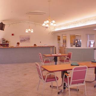 An empty reception area with tables and chairs, featuring tiled flooring and decorative lighting.