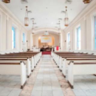 A view of a church interior with pews and an altar at the front.