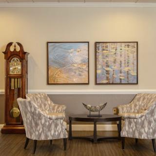 A cozy living room corner featuring elegant chairs, wall art, and a classic clock.