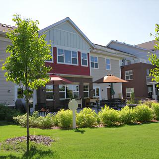 A modern residential building with a well-maintained lawn and outdoor seating area.