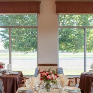A beautifully set dining area with large windows and floral centerpieces.