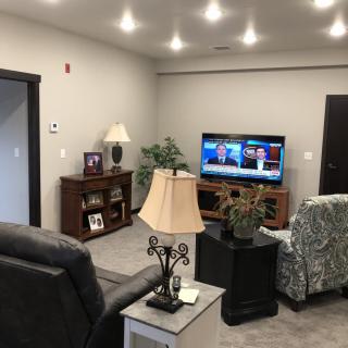 A cozy living room with a TV, sofas, and decorative lamps.