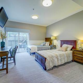 A cozy bedroom with two beds, a desk, and a TV mounted on the wall.