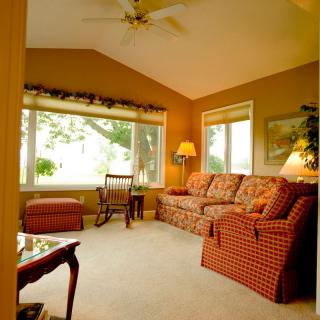 A cozy living room with a sofa, chair, and large windows allowing natural light.