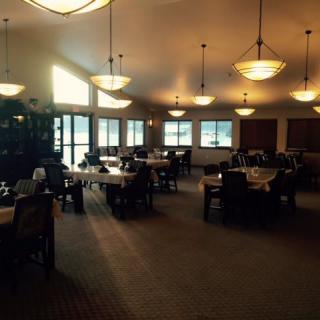 An empty restaurant dining room with large windows and elegant lighting.