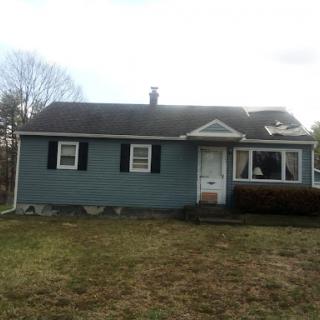 A cozy single-story house with green siding and a front lawn.