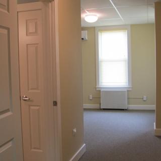 A view of an empty room with a window and hallway.