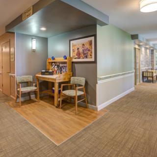 A cozy hallway corner with a wooden desk and two chairs, accented by artwork on the wall.
