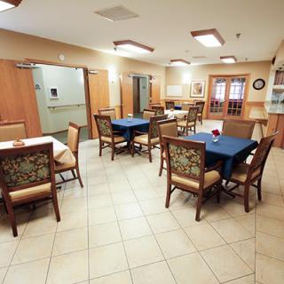 An empty dining area with neatly arranged tables and chairs, featuring warm lighting and a welcoming atmosphere.