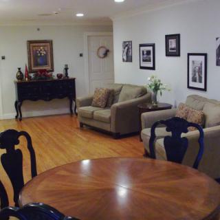 A cozy living room with sofas, a wooden table, and various artworks on the walls.
