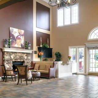 A spacious lobby with a cozy fireplace and seating area, adorned with elegant furniture and a chandelier.
