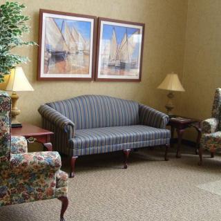 A cozy living room with a striped sofa, floral armchairs, and nautical-themed artwork on the wall.
