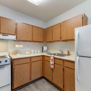 A cozy kitchen with wooden cabinets, a refrigerator, stove, and sink.