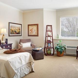 A cozy bedroom with a comfortable armchair, stylish decor, and natural light streaming through the window.