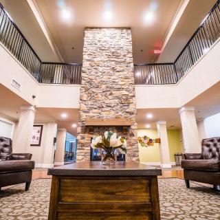 A modern lobby featuring a central stone fireplace and comfortable seating area.