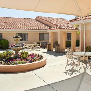 A peaceful courtyard with garden and outdoor seating, featuring a sunshade and well-maintained landscaping.