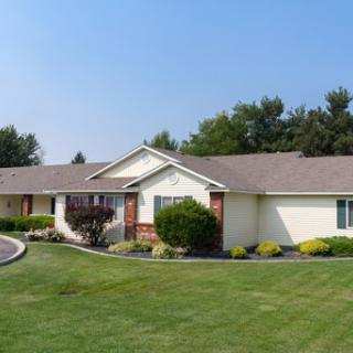 A charming single-story house with a well-maintained lawn under a clear blue sky.