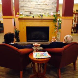 A couple holding hands and relaxing in front of a fireplace.
