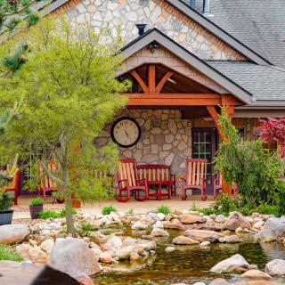 A charming stone house with a landscaped garden and pond in the foreground.