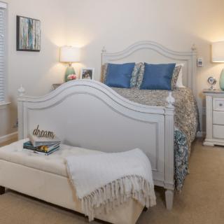 A cozy bedroom with white furniture and blue accents.