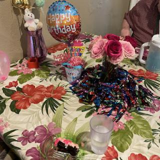 A colorful birthday celebration setup with floral decorations, a cheerful balloon, and party items.