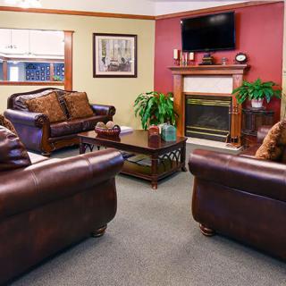 A cozy living room with leather sofas, a fireplace, and a mounted TV.
