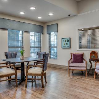 A modern dining area with a stylish table and chairs, surrounded by large windows and decorated with artwork.