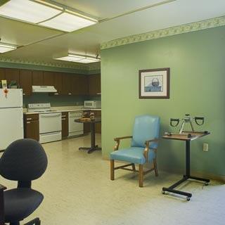 A kitchen area with appliances, chairs, and a small table.