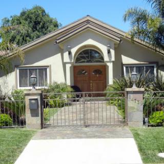 A beautiful residential house with a well-maintained front yard and decorative gate.