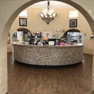 A welcoming reception area with a modern curved front desk and elegant chandelier.