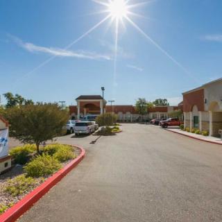 A bright sunny day in a parking lot with buildings and vehicles.