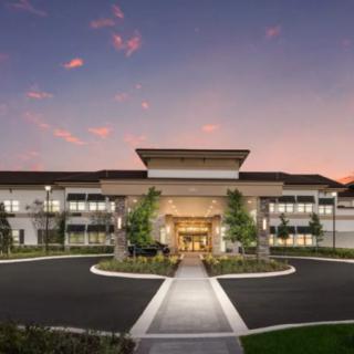 A modern building at sunset with a welcoming entrance and landscaped surroundings.