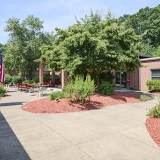 A peaceful outdoor area featuring well-maintained landscaping, a pathway, and an American flag.