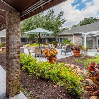 A tranquil courtyard featuring lush gardens and outdoor seating with umbrellas.