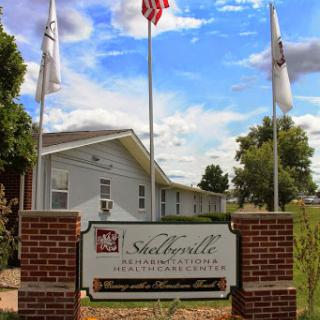 A welcoming entrance sign at a community facility, framed by flags and a clear blue sky.