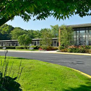 A modern building surrounded by a well-maintained landscape with trees and lush grass.