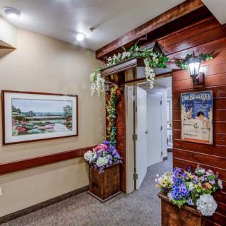 A warmly decorated hallway with floral arrangements and framed artwork.