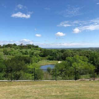 A scenic landscape with a pond surrounded by lush greenery and a clear blue sky overhead.