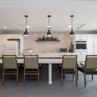 A modern kitchen and dining area with a large island, pendant lighting, and sleek decor.
