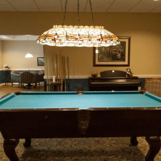 A game room featuring a pool table under decorative lighting.