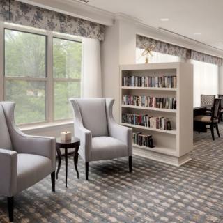 A cozy reading corner with elegant chairs and a bookshelf in a well-lit room.