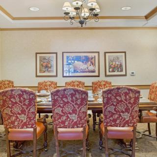 A well-furnished conference room with a long table, patterned chairs, wall art, and a chandelier.
