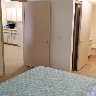 A view from a bedroom looking into a kitchen area through open doors.