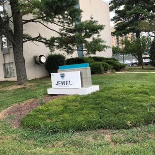 The outdoor sign for Jewel, situated in a green landscape.