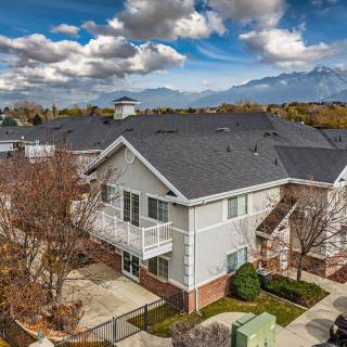 A suburban house with a scenic mountain backdrop and partly cloudy skies.