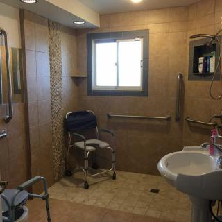 An accessible bathroom equipped with a shower chair, grab bars, and other amenities to assist individuals with mobility needs.
