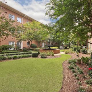 A beautifully landscaped garden with a fountain in an apartment complex courtyard.