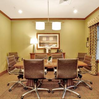 A well-lit conference room with a central table and six office chairs.